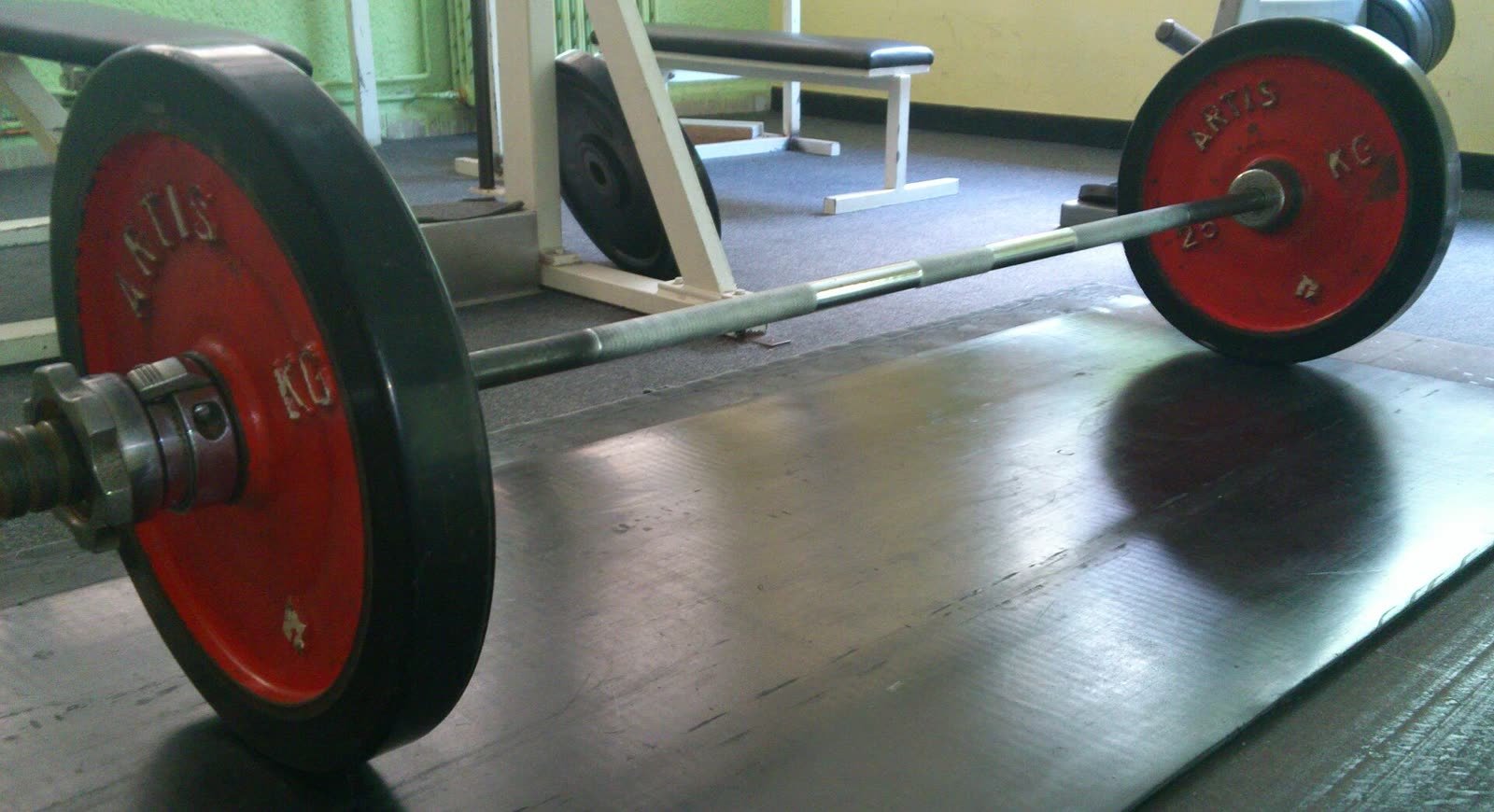 An Olympic barbell with plates on a gym floor